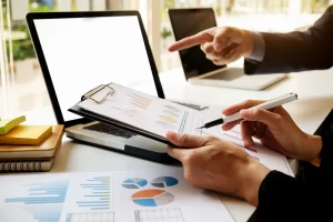 Business professionals reviewing financial reports and charts while discussing outsourced financial record management solutions