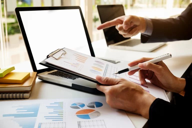 Business professionals reviewing financial reports and charts while discussing outsourced financial record management solutions