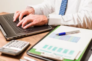 Professional working on laptop with financial reports and calculator representing offshore accounting practices for SMEs maintaining accurate financial records