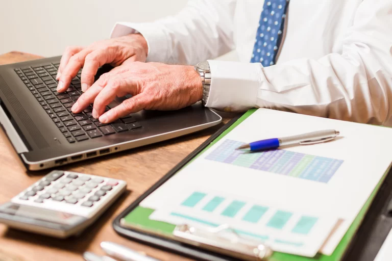 Professional working on laptop with financial reports and calculator representing offshore accounting practices for SMEs maintaining accurate financial records