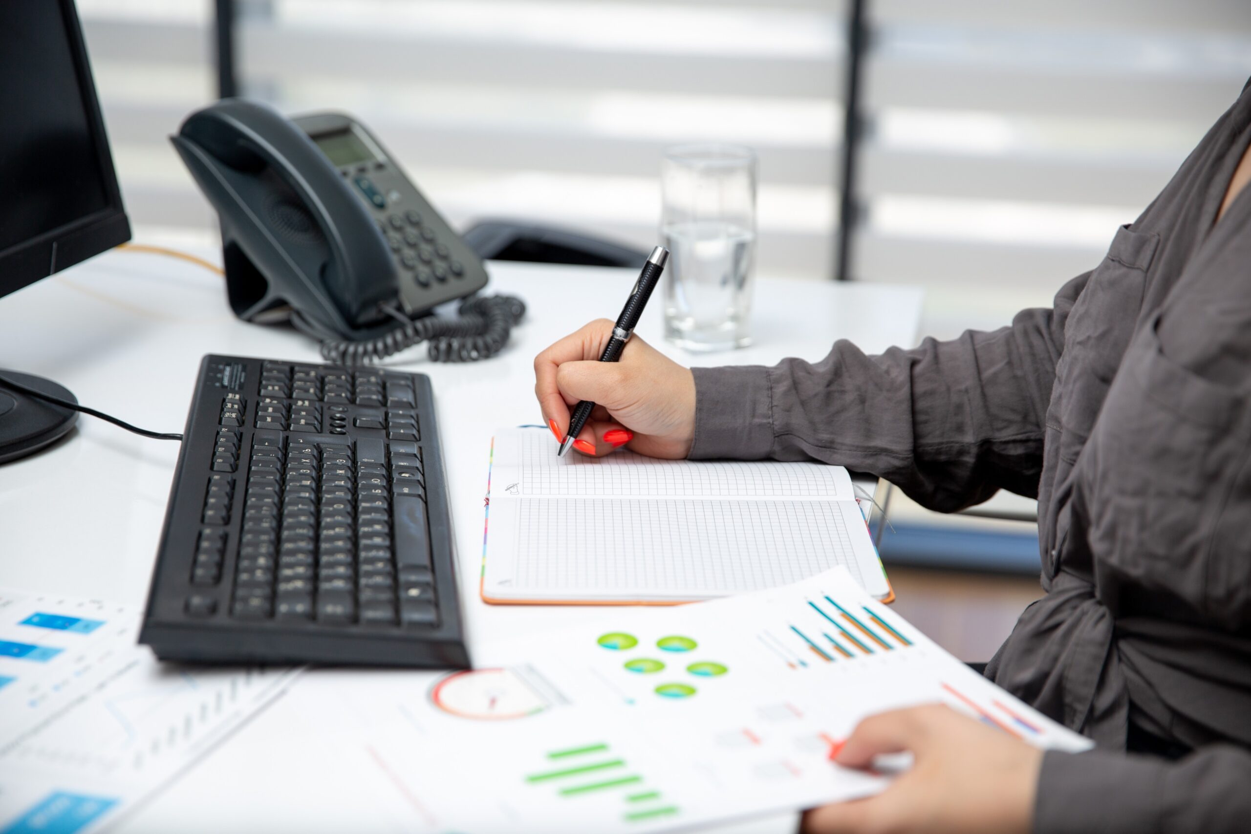 Small business owner reviewing financial reports and bookkeeping records at an office desk.
